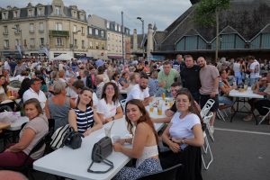 Moment convivial partagé lors du marché gourmand place Fernand Marquigny, réunissant de nombreux habitants autour de grandes tablées.