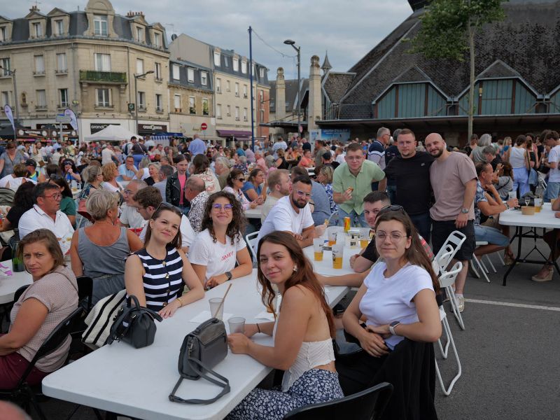Moment convivial partagé lors du marché gourmand place Fernand Marquigny, réunissant de nombreux habitants autour de grandes tablées.