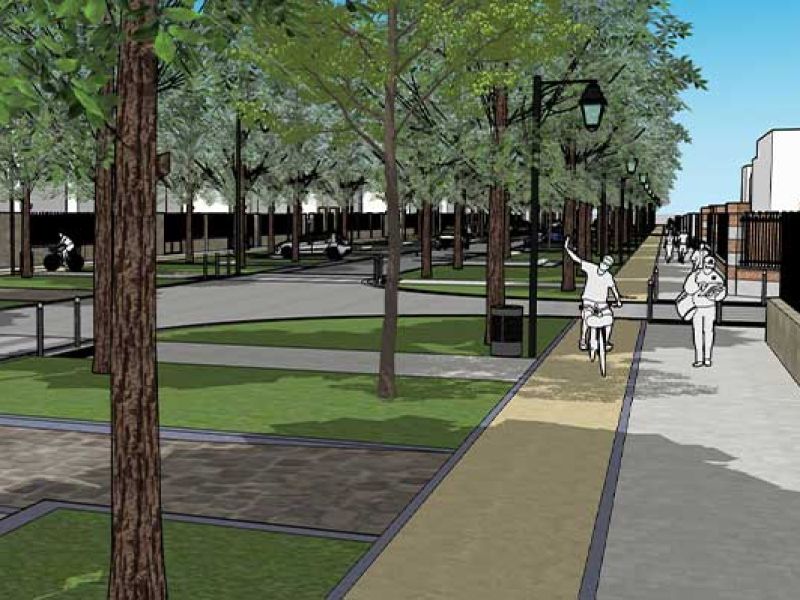 Vue d'un boulevard à Soissons, montrant une large allée bordée d'arbres et de lampadaires. Des personnes se promènent et font du vélo sur un chemin pavé. Des espaces verts avec de l'herbe et des zones de repos sont visibles de part et d'autre du boulevar