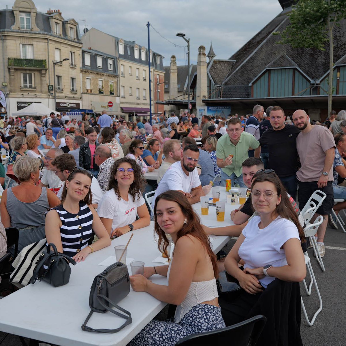 Moment convivial partagé lors du marché gourmand place Fernand Marquigny, réunissant de nombreux habitants autour de grandes tablées.