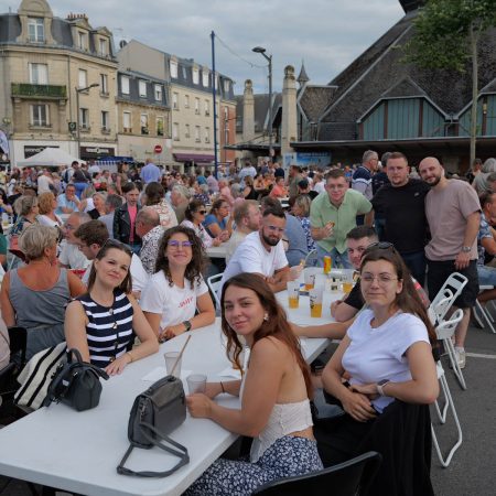 Moment convivial partagé lors du marché gourmand place Fernand Marquigny, réunissant de nombreux habitants autour de grandes tablées.